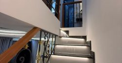 Cầu thang đá đen có đèn LED dưới mỗi bậc và lan can sắt mỹ thuật trang trí màu vàng