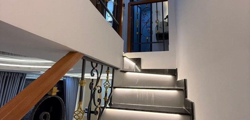 Cầu thang đá đen có đèn LED dưới mỗi bậc và lan can sắt mỹ thuật trang trí màu vàng